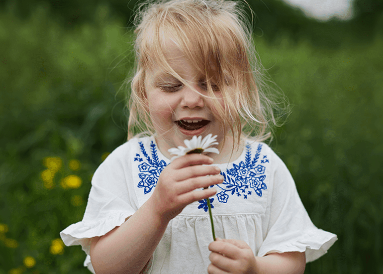 Une jeune fille, debout dehors et souriant dans une pâquerette