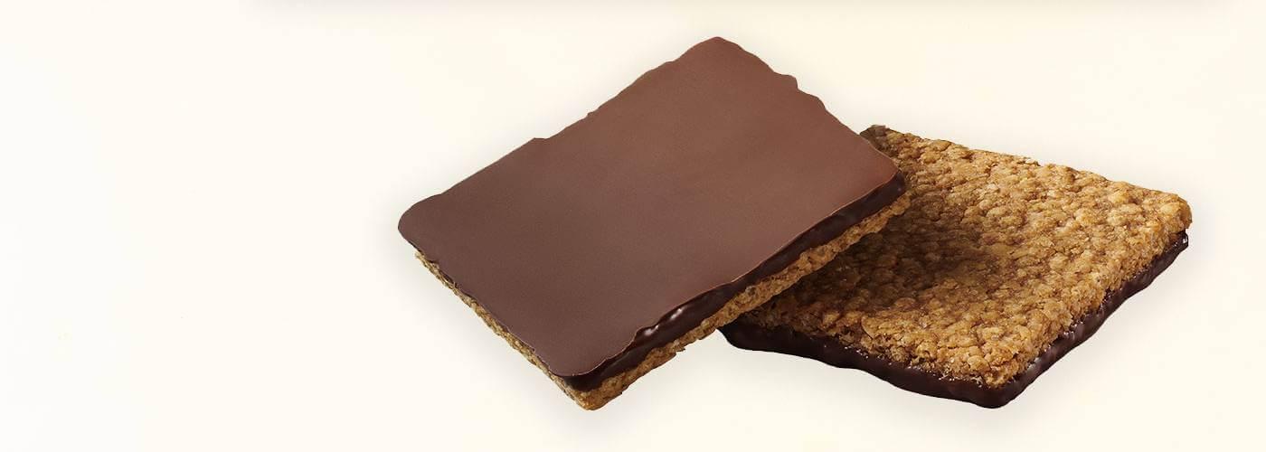 Deux carrés de granola trempés dans du chocolat croustillant. L'un d'eux est à l'envers, montrant la couche de chocolat.