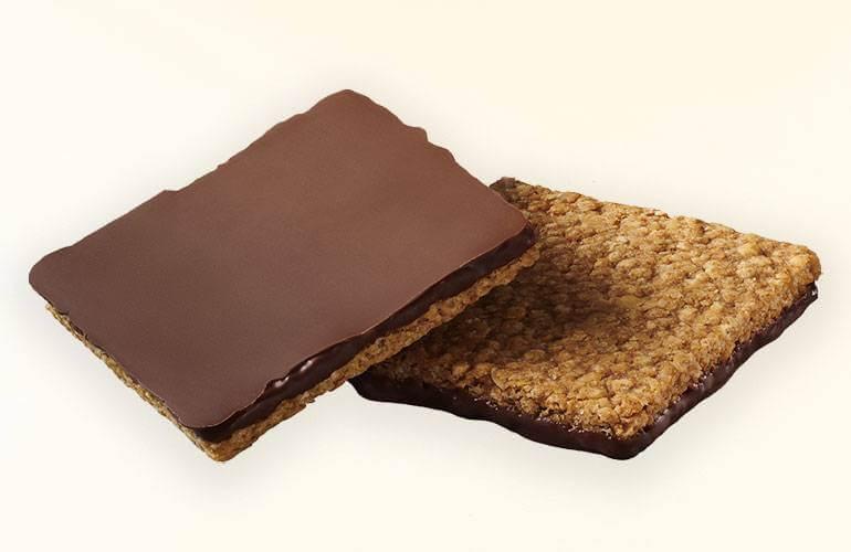 Deux carrés de granola trempés dans du chocolat croustillant. L'un d'eux est à l'envers, montrant la couche de chocolat