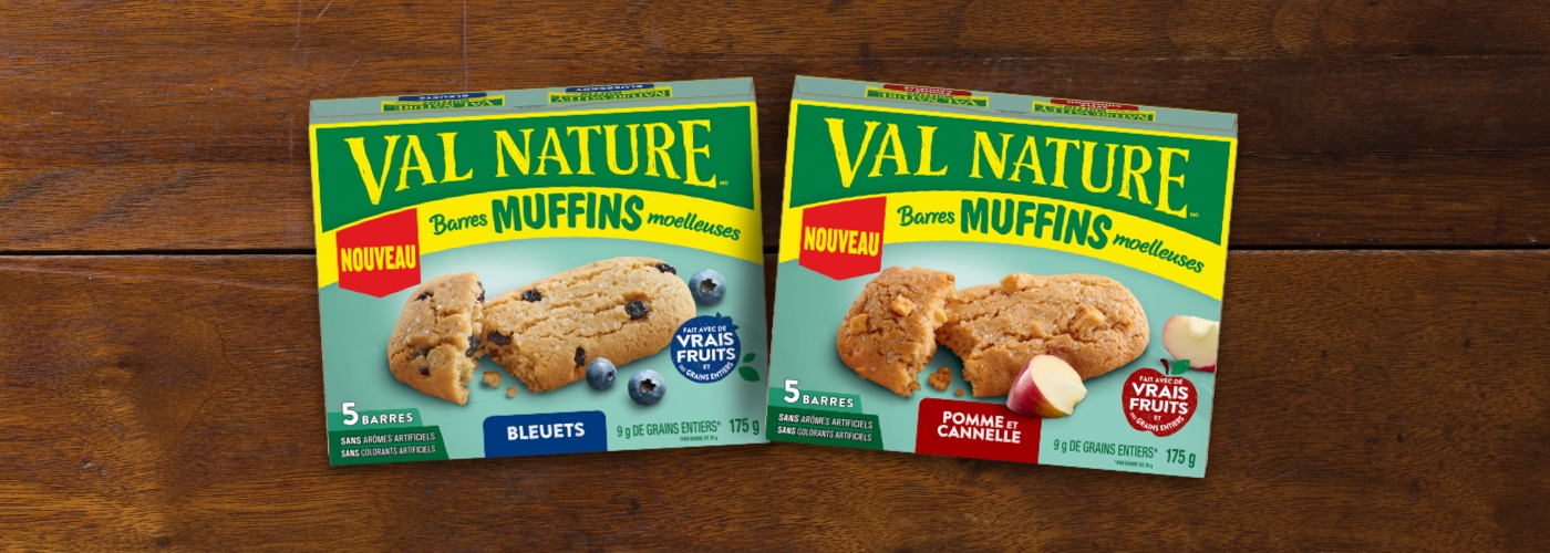 Two front-facing pack shots of Nature Valley Soft Baked Muffins Bars in the flavors Blueberry and Apple Cinnamon on a wood-colored background.